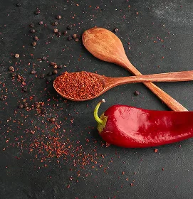 Piment rouge entier et poudre de piment sur des cuillères en bois