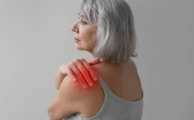 Femme en débardeur gris portant la main à son épaule
